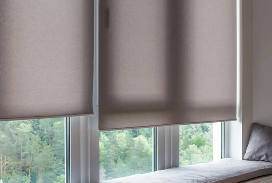 Beige Rollos an großen Fenstern mit Blick ins Grüne. Moderner Sichtschutz und Sonnenschutz für Wohnräume mit stilvoller Fensterdekoration und natürlichem Lichteinfall